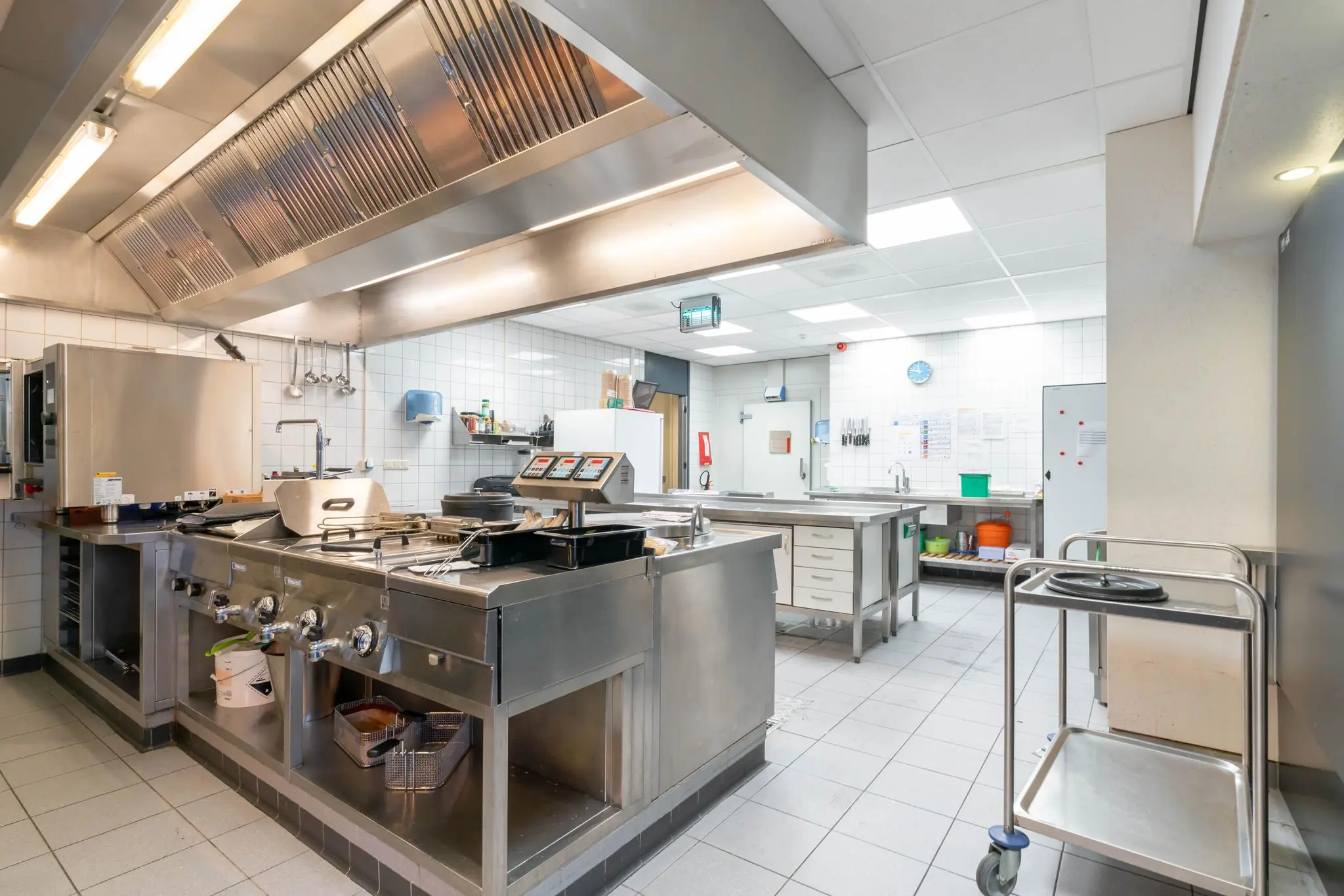 Professionele, ruime horecakeuken aan de De Bruyn Kopsstraat met moderne RVS-apparatuur en tegelwanden.